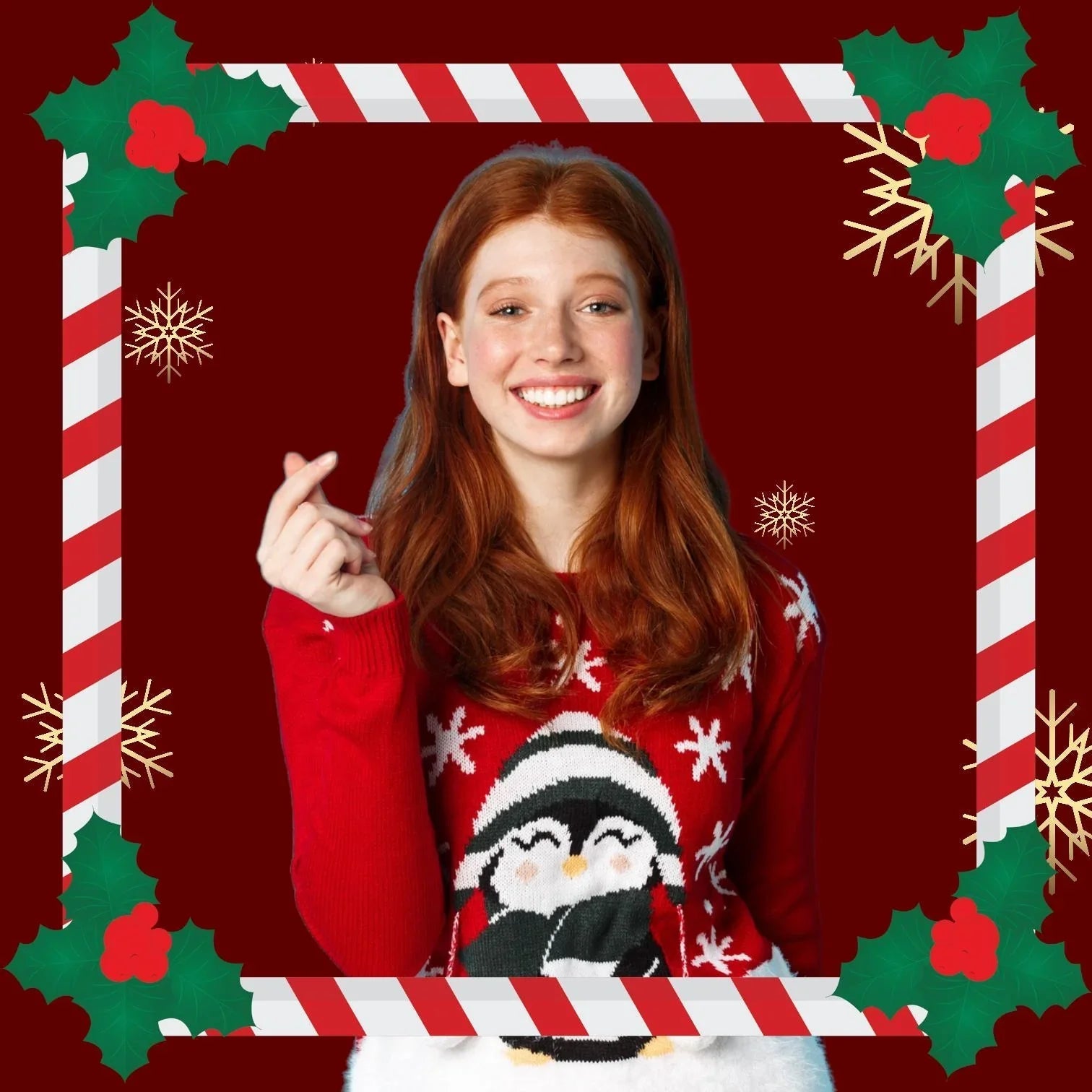Junge Frau mit roten Haaren lächelt im roten Weihnachtspullover mit Pinguin-Motiv, weihnachtlicher Rahmen und Schneeflocken, feinkostgourmet festliche Stimmung