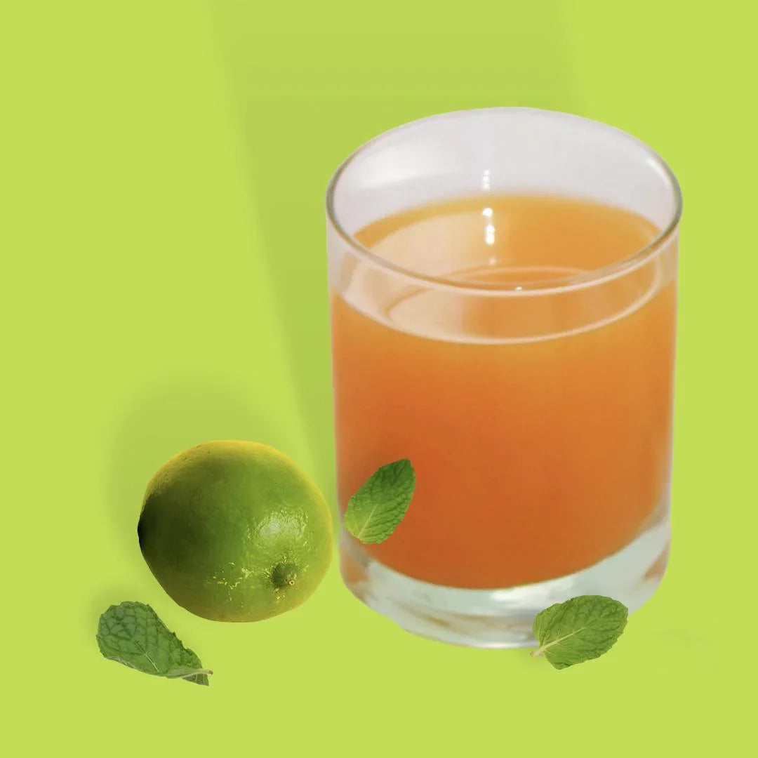 Glas mit orangem Getränk, Limette und Minzblättern auf grünem Hintergrund, Feinkostgourmet