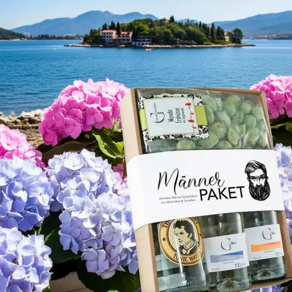 feinkostgourmet Männerpaket Geschenkset mit Delikatessen und Getränken vor Blumen und See