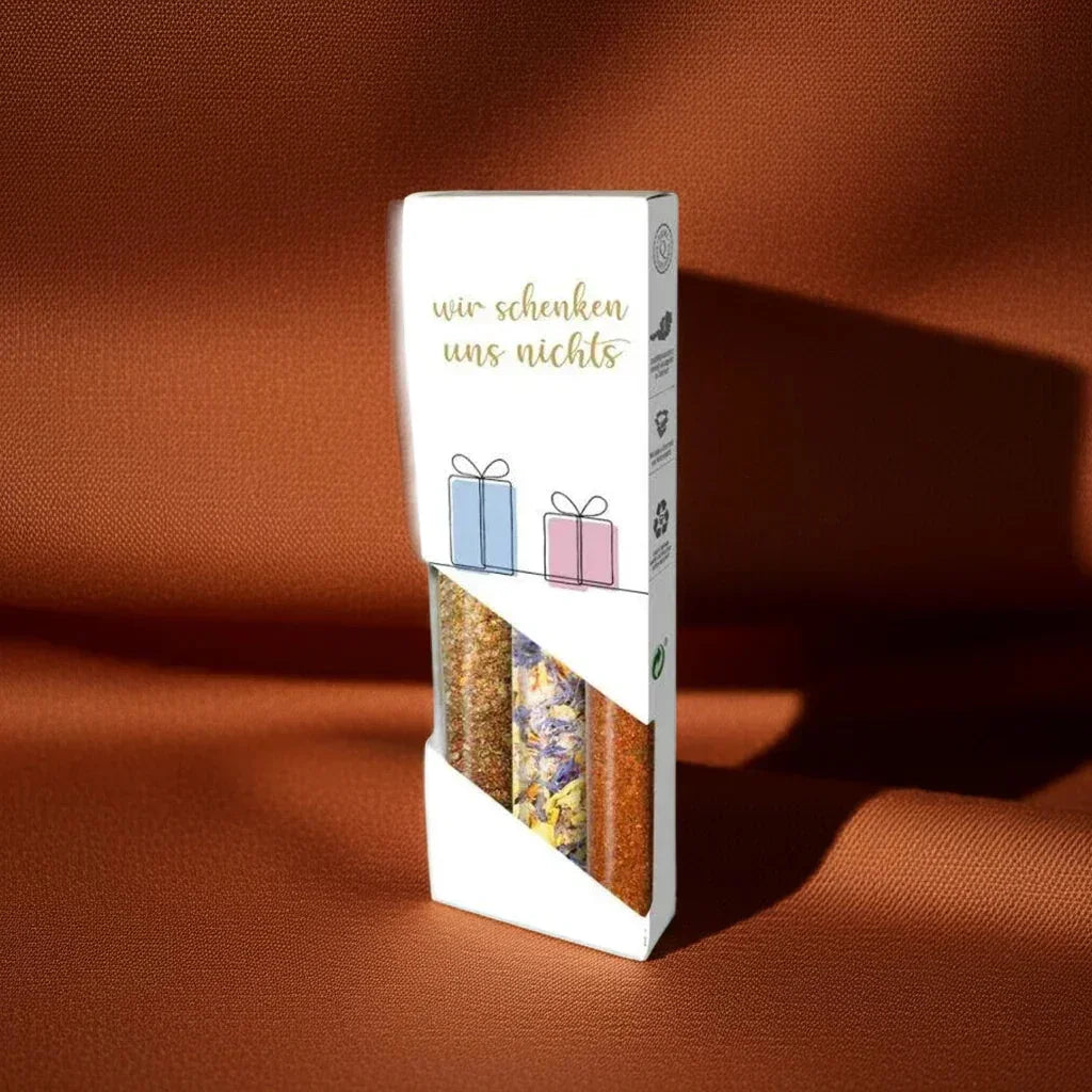 Geschenkbox mit drei Gewürzmischungen von feinkostgourmet, vor braunem Hintergrund